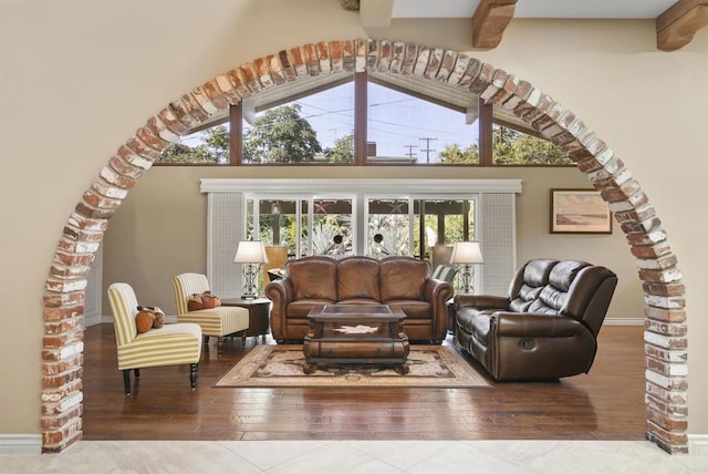 living room with hardwood / wood-style flooring, beamed ceiling, and a towering ceiling