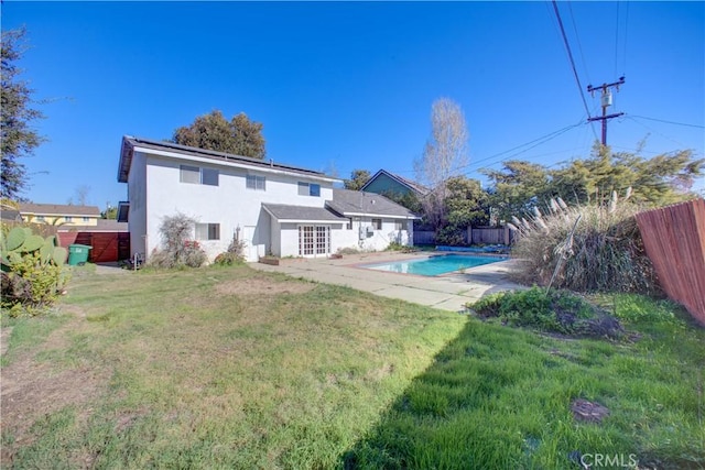 back of property featuring a fenced in pool, a patio area, and a lawn