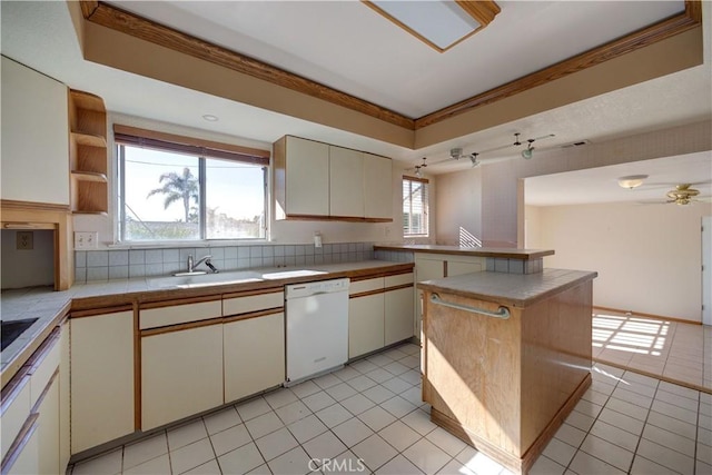 kitchen featuring a center island, sink, white dishwasher, light tile patterned floors, and cream cabinetry