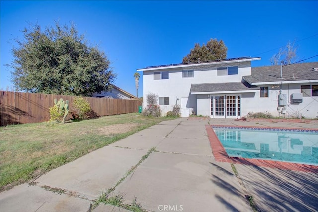 back of house featuring a yard, french doors, a patio area, and a fenced in pool