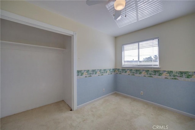 unfurnished bedroom featuring ceiling fan, light colored carpet, and a closet