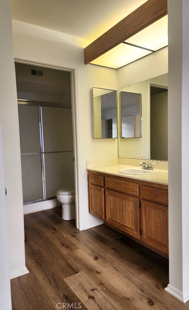 bathroom featuring an enclosed shower, vanity, wood-type flooring, and toilet