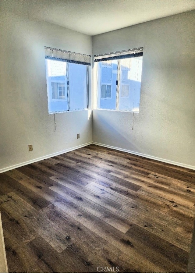 spare room featuring plenty of natural light and dark hardwood / wood-style flooring