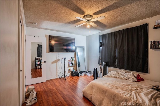 bedroom featuring ceiling fan, wood-type flooring, and a textured ceiling