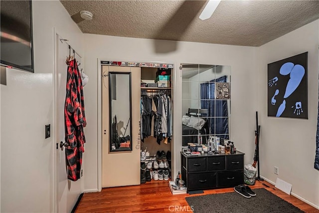 bedroom featuring ceiling fan, a textured ceiling, wood-type flooring, and a closet