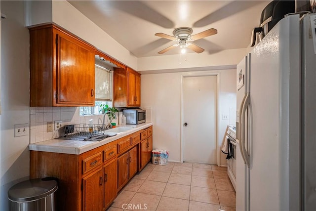 kitchen with white appliances, backsplash, tile countertops, ceiling fan, and light tile patterned floors