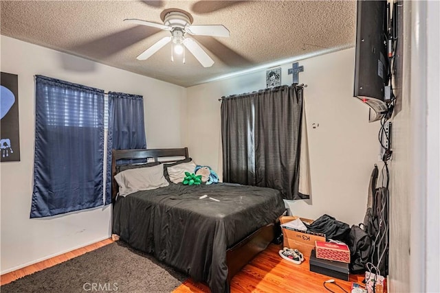 bedroom with a textured ceiling, ceiling fan, and hardwood / wood-style flooring