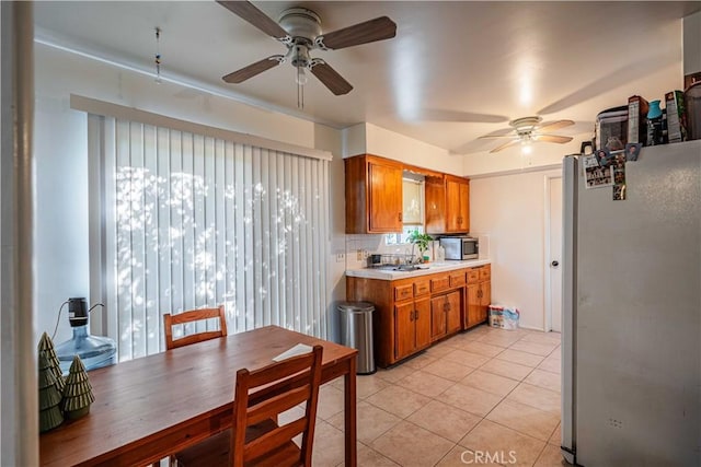 kitchen featuring ceiling fan, backsplash, refrigerator, and light tile patterned flooring