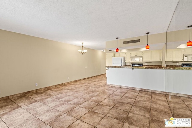 kitchen featuring decorative light fixtures, light tile patterned floors, refrigerator, and an inviting chandelier