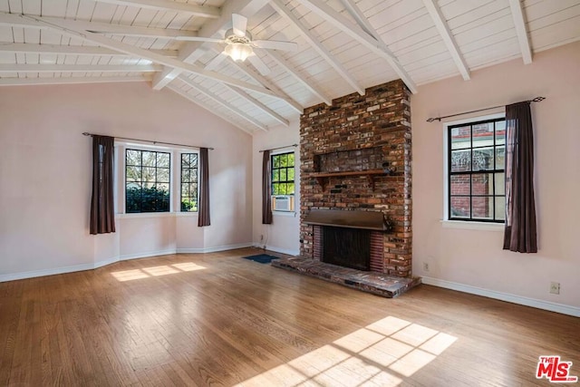 unfurnished living room featuring lofted ceiling with beams, wood-type flooring, a brick fireplace, and ceiling fan