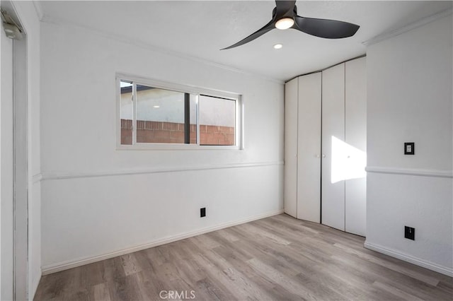 unfurnished bedroom featuring ceiling fan, a closet, crown molding, and light hardwood / wood-style flooring