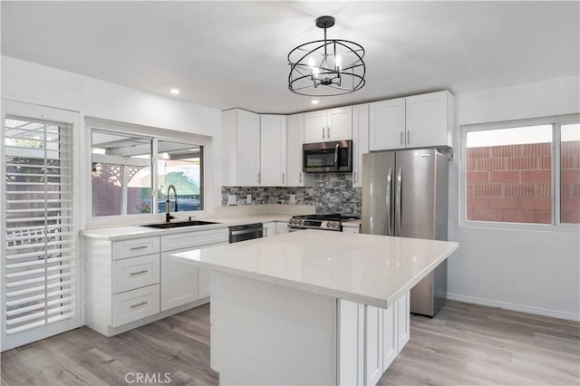 kitchen with a center island, sink, hanging light fixtures, appliances with stainless steel finishes, and white cabinets