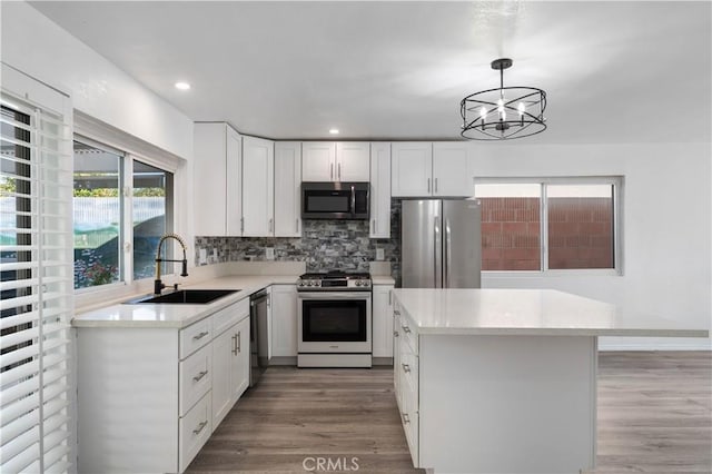 kitchen with stainless steel appliances, backsplash, pendant lighting, white cabinets, and sink