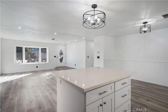 kitchen with a kitchen island, an inviting chandelier, white cabinetry, hardwood / wood-style flooring, and hanging light fixtures