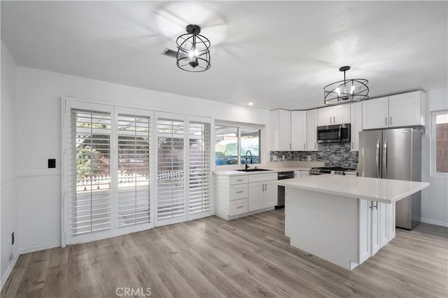 kitchen featuring decorative light fixtures, white cabinetry, stainless steel appliances, tasteful backsplash, and sink