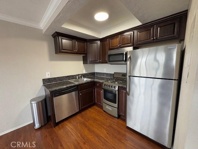 785 W 19th St Unit 12B, San Pedro, CA 90731 - kitchen with stainless steel appliances, dark countertops, dark brown cabinets, dark wood finished floors, and crown molding