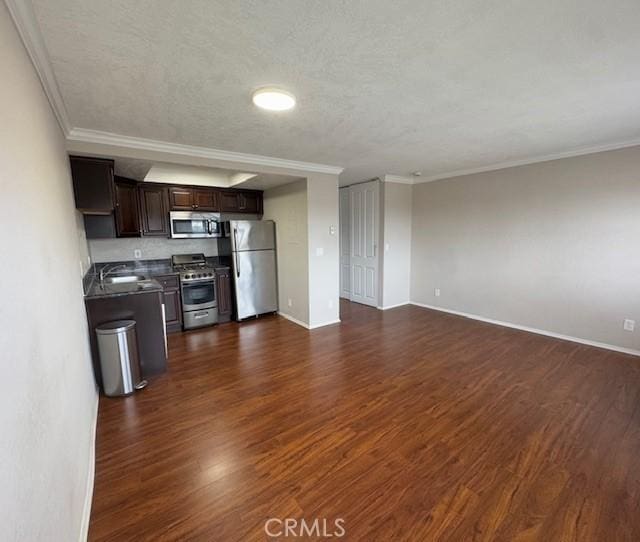 kitchen with stainless steel appliances, dark countertops, open floor plan, and dark wood-style floors