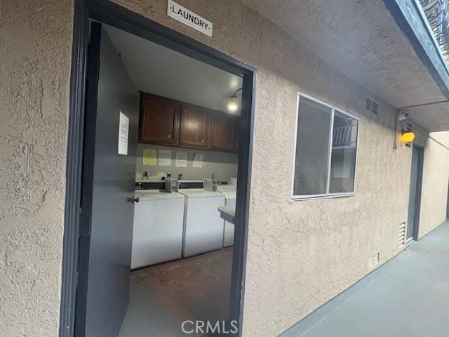 exterior space with cabinet space, a textured wall, and washer and clothes dryer