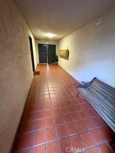 hall featuring a textured wall and tile patterned floors