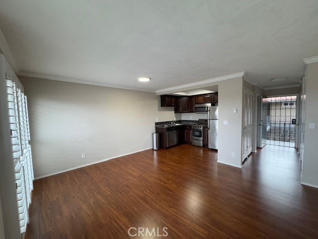 unfurnished living room with ornamental molding and dark hardwood / wood-style floors