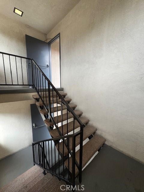 staircase with concrete flooring and a textured wall