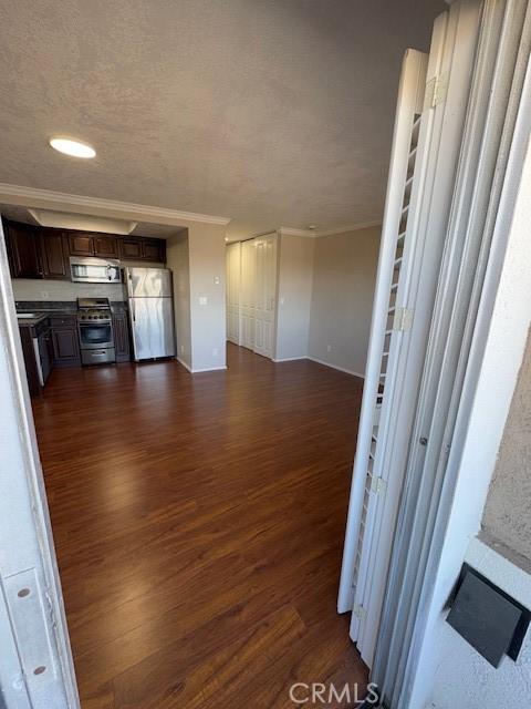 kitchen with crown molding, dark hardwood / wood-style flooring, dark brown cabinetry, and appliances with stainless steel finishes