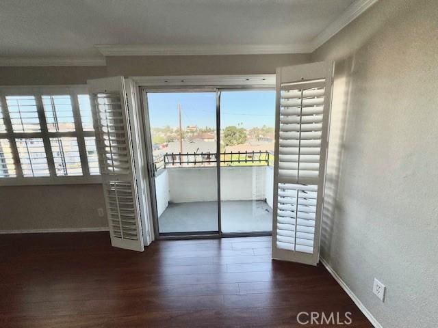 empty room featuring dark wood-style flooring, crown molding, and baseboards