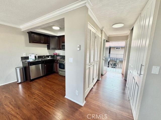 785 W 19th St Unit 12B, San Pedro, CA 90731 - kitchen featuring appliances with stainless steel finishes, a textured ceiling, dark wood finished floors, dark brown cabinets, and crown molding