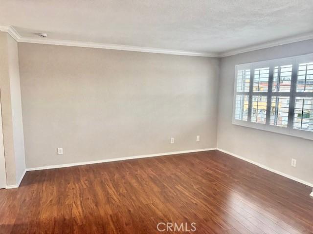 785 W 19th St Unit 12B, San Pedro, CA 90731 - spare room featuring crown molding and dark wood-style floors