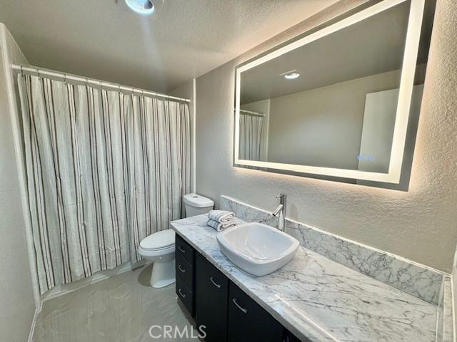 785 W 19th St Unit 12B, San Pedro, CA 90731 - full bathroom featuring a textured wall, vanity, marble finish floors, a shower with shower curtain, and a textured ceiling