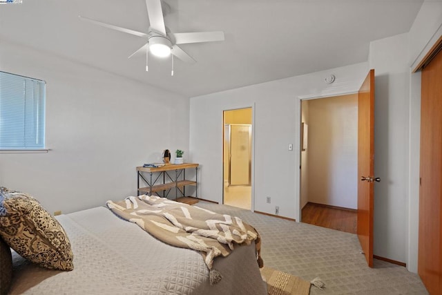 bedroom with light carpet, ceiling fan, a closet, and ensuite bath