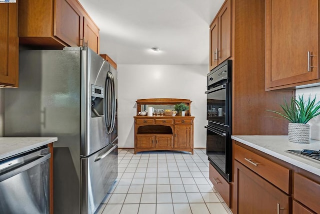 kitchen with light tile patterned flooring, appliances with stainless steel finishes, and light stone countertops