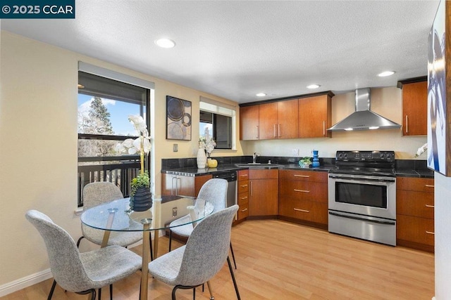 kitchen featuring wall chimney exhaust hood, sink, a textured ceiling, appliances with stainless steel finishes, and light hardwood / wood-style floors