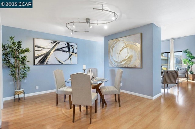 dining area featuring rail lighting and light hardwood / wood-style floors