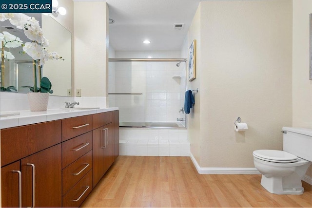 full bathroom with vanity, wood-type flooring, combined bath / shower with glass door, and toilet