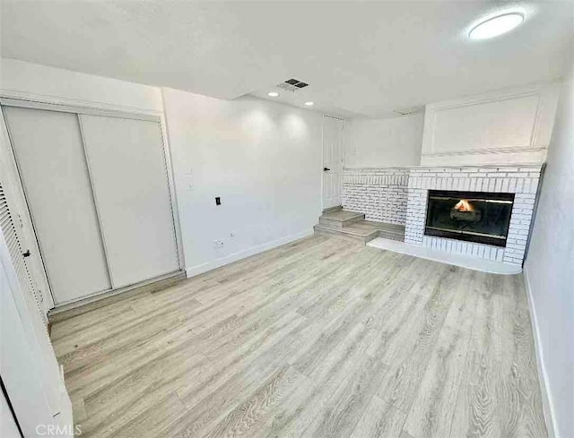 unfurnished living room with a fireplace and light hardwood / wood-style floors