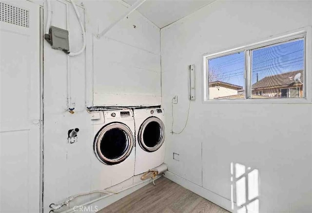 laundry room with independent washer and dryer and light hardwood / wood-style flooring