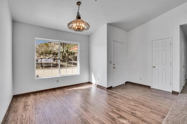 spare room with an inviting chandelier and hardwood / wood-style floors