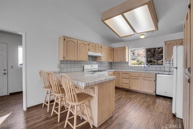 kitchen with a breakfast bar area, backsplash, white appliances, lofted ceiling, and sink