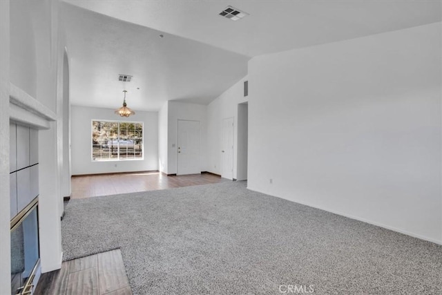 unfurnished living room featuring carpet floors, a notable chandelier, and lofted ceiling