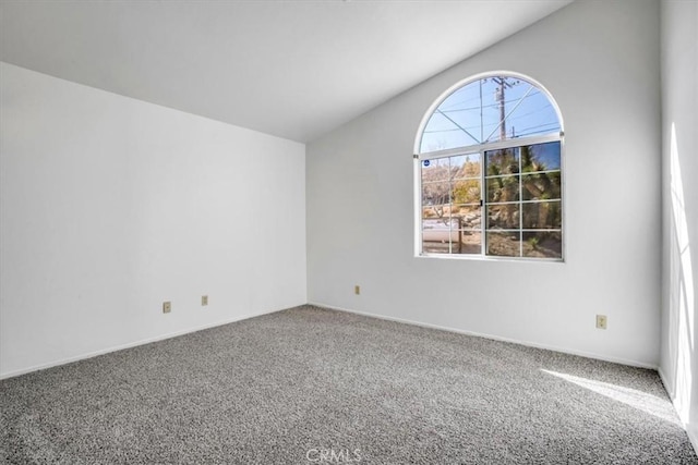 carpeted empty room featuring vaulted ceiling