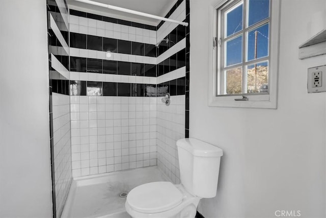 bathroom featuring toilet and a tile shower