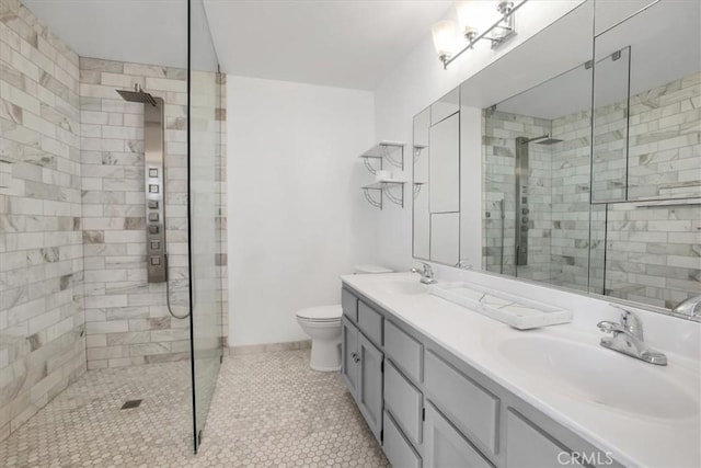 bathroom featuring toilet, vanity, tile patterned flooring, and a tile shower