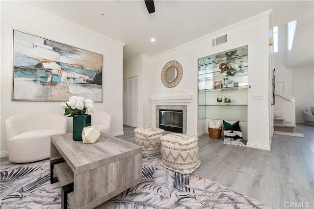 living room featuring a fireplace, crown molding, and light hardwood / wood-style flooring