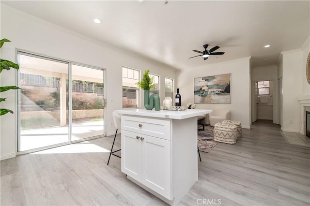 kitchen with an island with sink, white cabinets, a kitchen breakfast bar, and light hardwood / wood-style floors