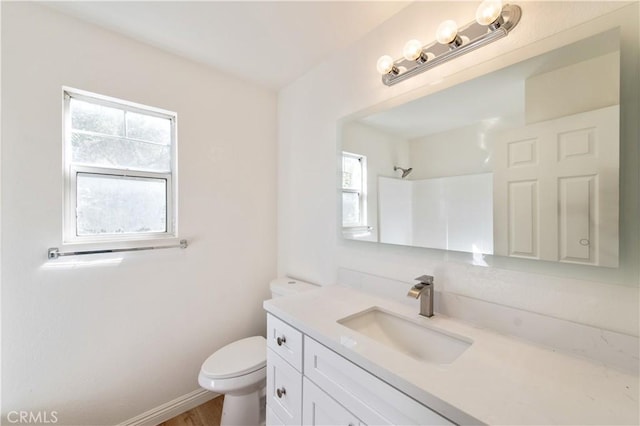 bathroom with toilet, a healthy amount of sunlight, a shower, and vanity