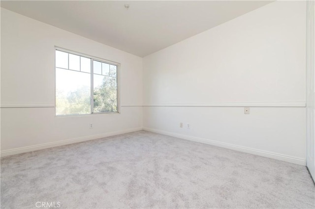 carpeted spare room with vaulted ceiling