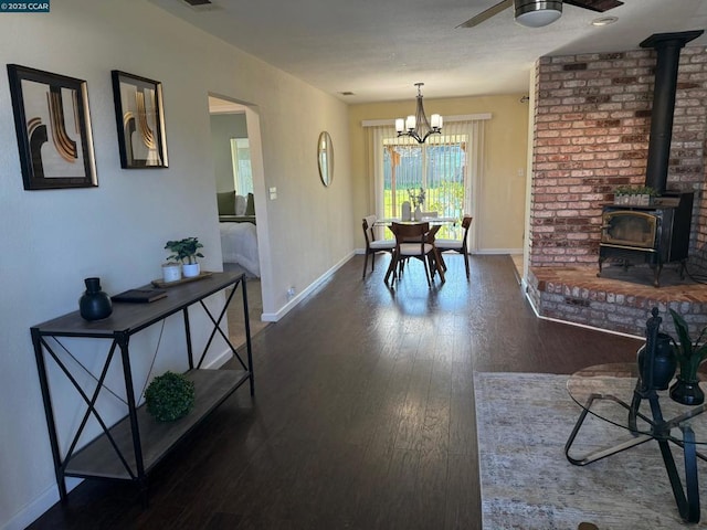 dining room featuring ceiling fan, a wood stove, and dark hardwood / wood-style flooring