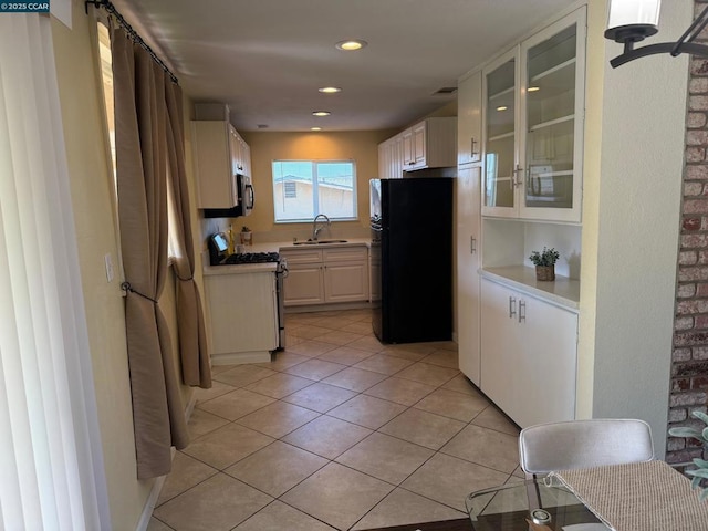 kitchen with white cabinetry, sink, light tile patterned floors, and stainless steel appliances