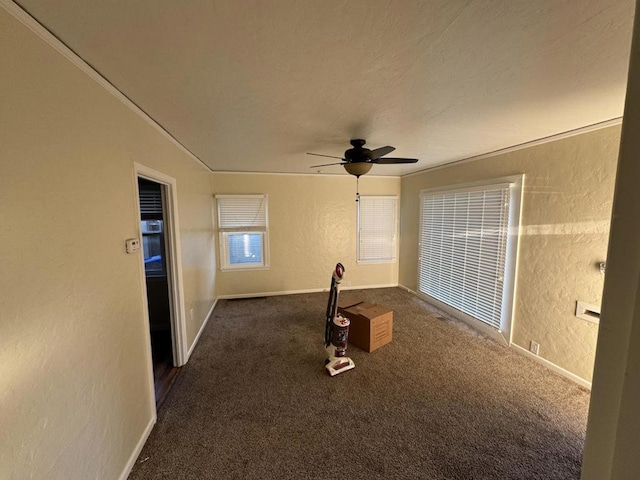 spare room featuring dark colored carpet, ceiling fan, and crown molding